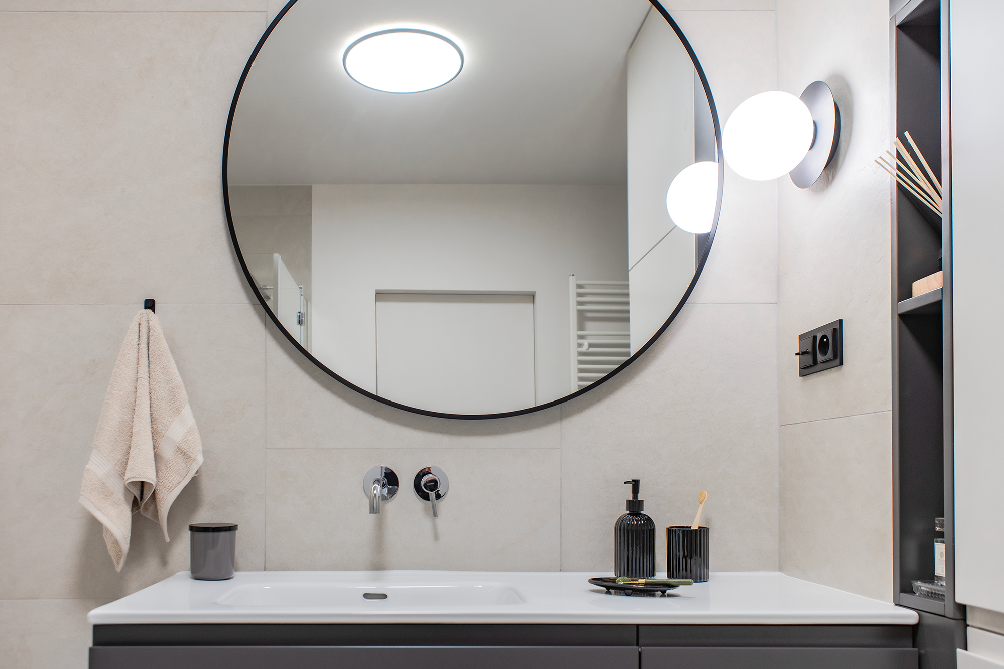 Po prawej stronie umywalki, znajduje się wysoka zabudowa meblowa ukrywająca pralkę. A otwarte półeczki, są wygodnym miejscem na podręczne przybory.